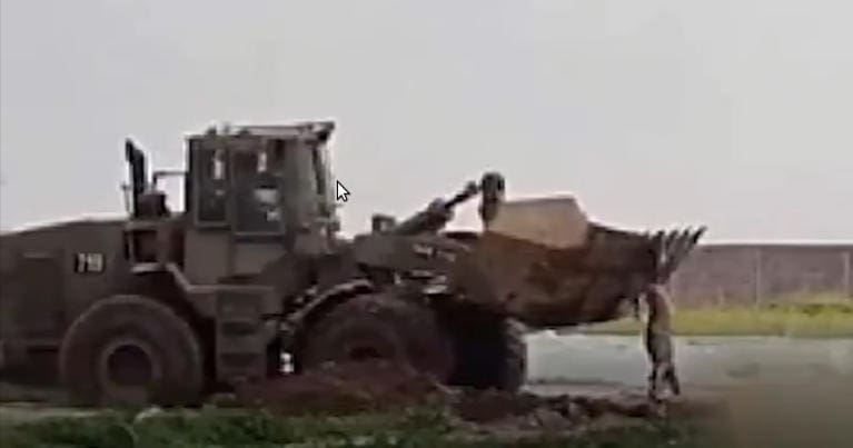 A Caterpillar bulldozer being used to move the body of Mohammed al-Naem in Gaza