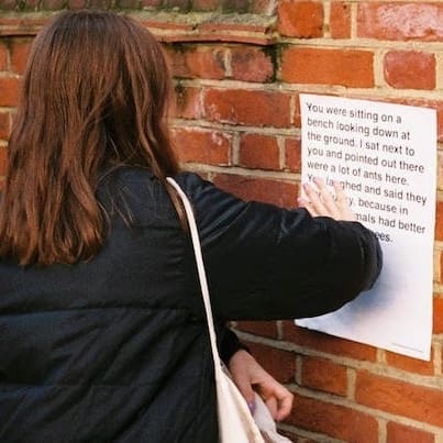 Woman. putting up a Conversations from Calais poster