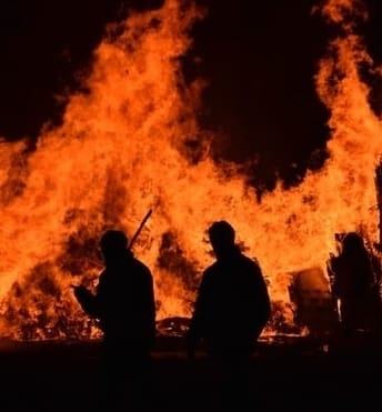 coronavirus and people walking past a large burning fire
