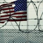 A tattered American flag behind razor wire