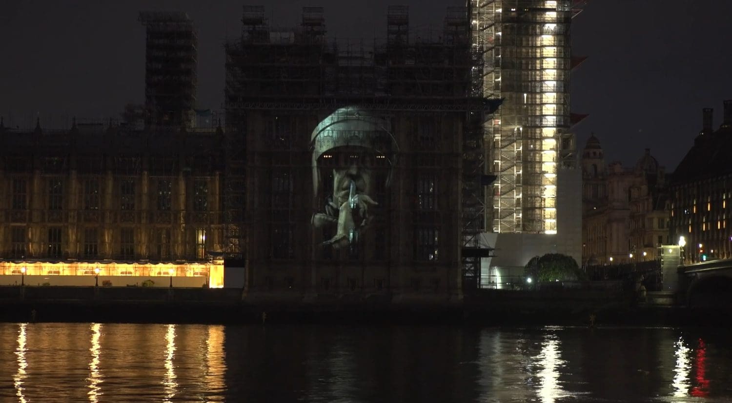Riot police officer demanding silence projected onto Houses of Parliament