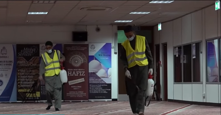 Workers wearing face masks and gloves cleaning inside a mosque