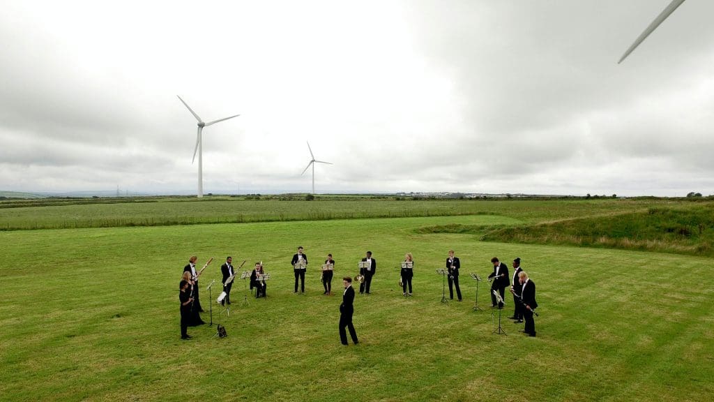Image of a wood wind orchestra playing in a wind farm
