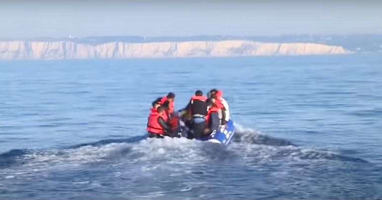 A group of refugees crammed into a small dinghy that's travelling across the Channel