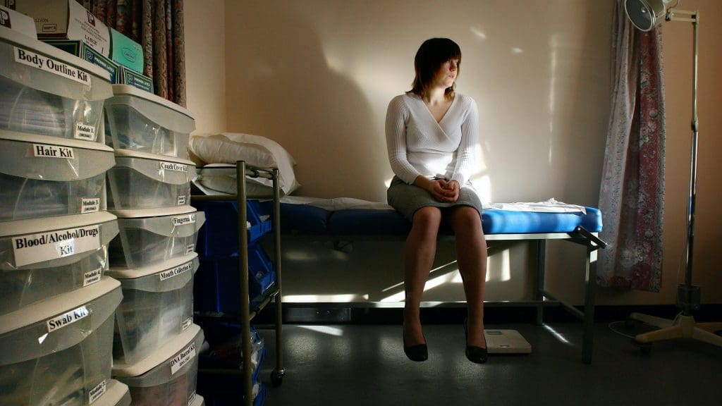 A woman sitting alone in a dark room staring into space