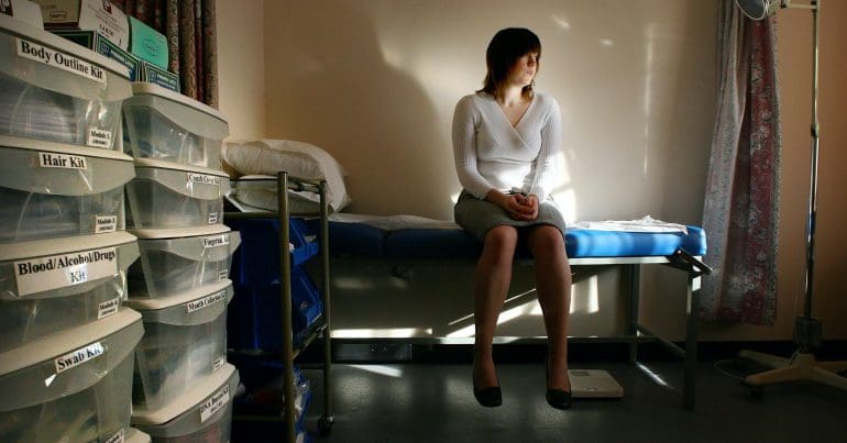 A woman sitting alone in a dark room staring into space