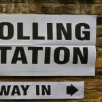 A poster that reads "polling station" with a smaller sign below pointing to the right