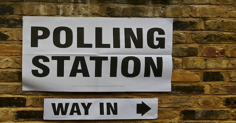 A poster that reads "polling station" with a smaller sign below pointing to the right