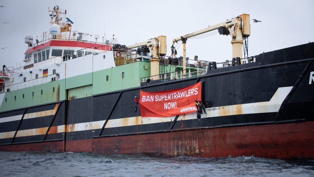A super trawler with a Greenpeace banner hanging off it that reads: 'BAN SUPERTRAWLERS NOW!'