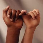 two people of colour link their hands together