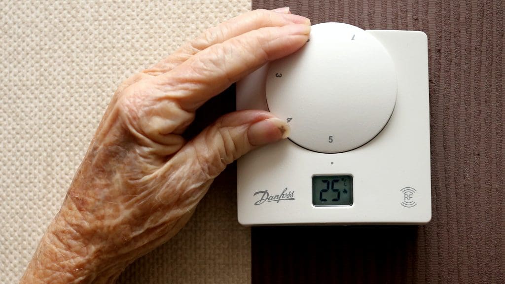 An old person's hand on a thermostat