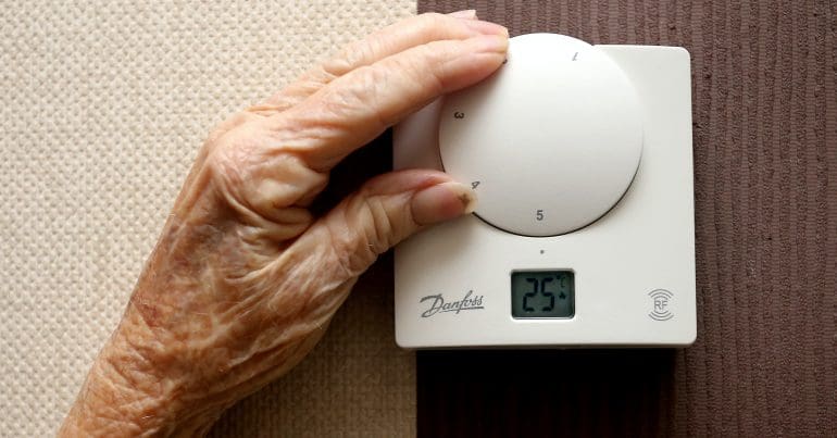 An old person's hand on a thermostat