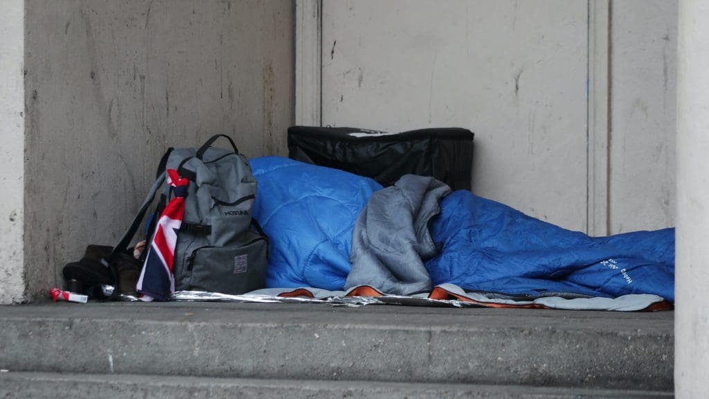 A person sleeping rough next to a building