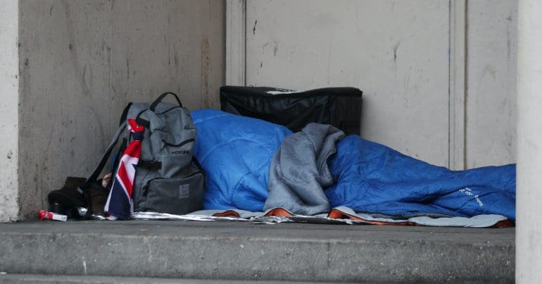 A person sleeping rough next to a building
