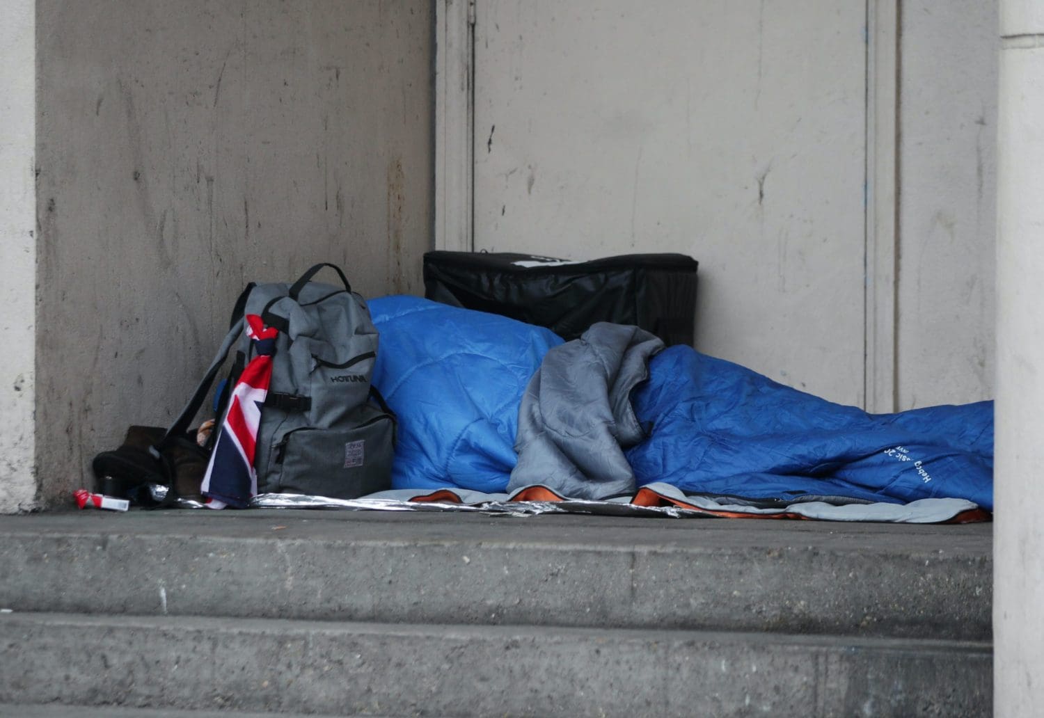 A person sleeping rough next to a building