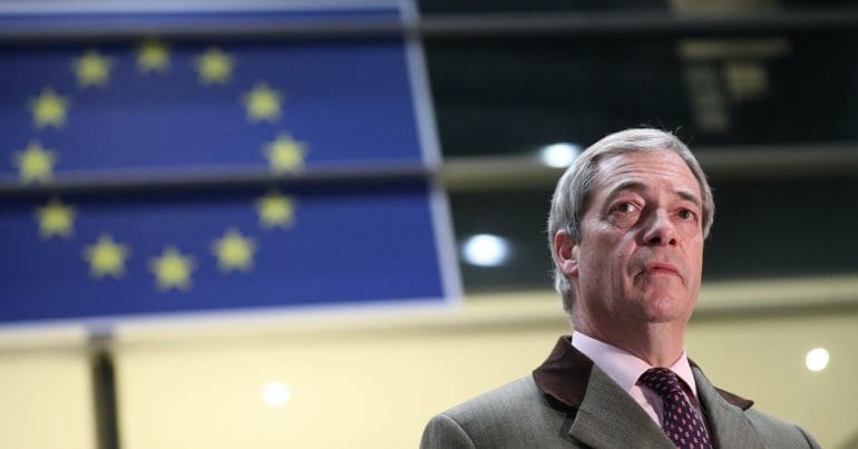 A sad looking Nigel Farage in front of an EU flag