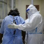 A patient with a doctor wearing a full suit of PPE