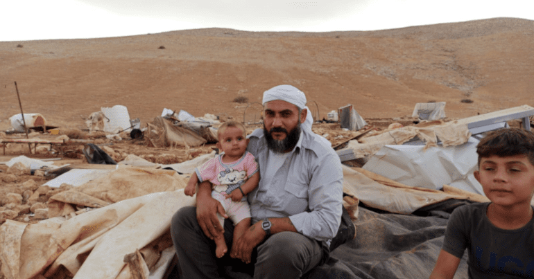 Palestinians sit amongst the ruins of the Humsa al Bqai’a Bedouin community