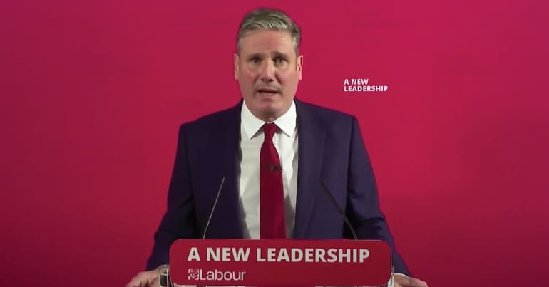 Keir Starmer standing in font of a sign which reads 'A new leadership'
