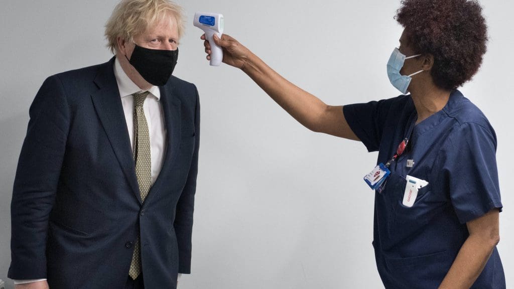 Boris Johnson wearing a mask having his temperature taken by a nurse