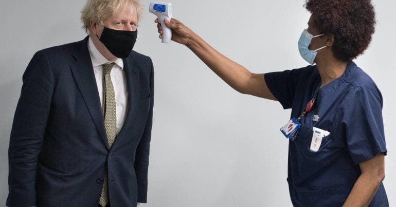 Boris Johnson wearing a mask having his temperature taken by a nurse