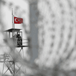 A Turkish flag flies on a prison watchtower