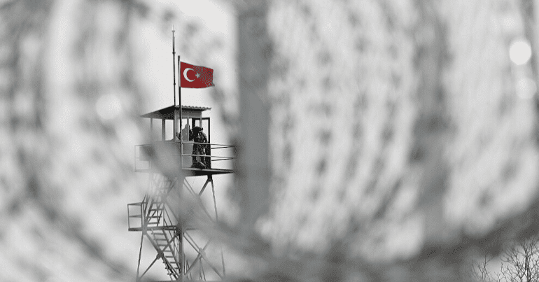 A Turkish flag flies on a prison watchtower