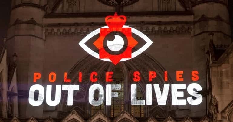 the 'Police spies out of lives' logo being projected onto a building