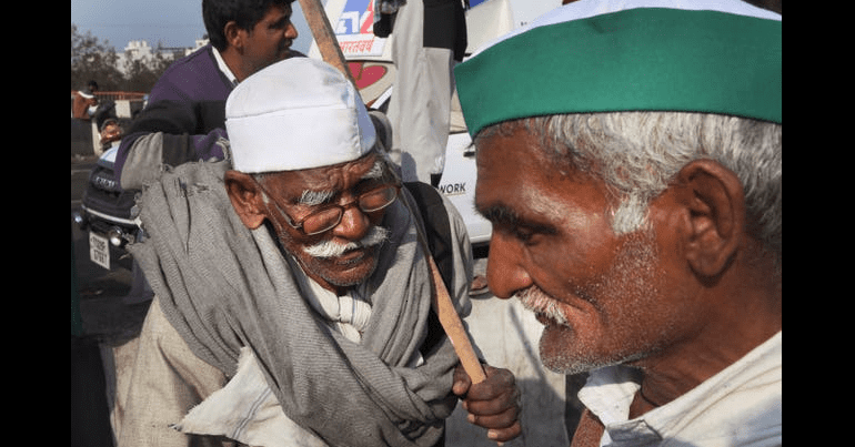 Elderly farmers talk on a heavily barricaded road outside New Delhi (AP)