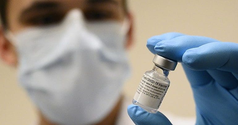 A scientist holding a vaccine vial