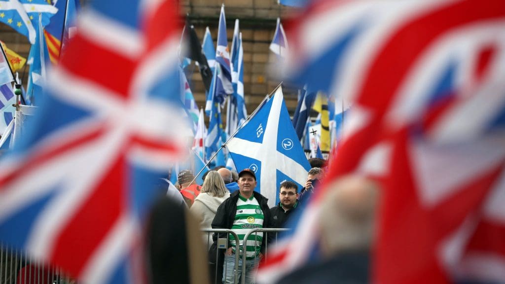 Scots with Saltires looking at a couple of Union Flags in the distance