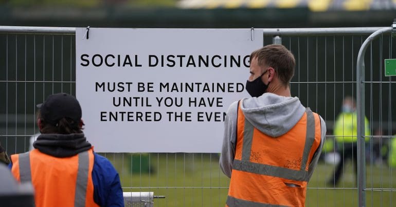 Workers besides a social distancing sign