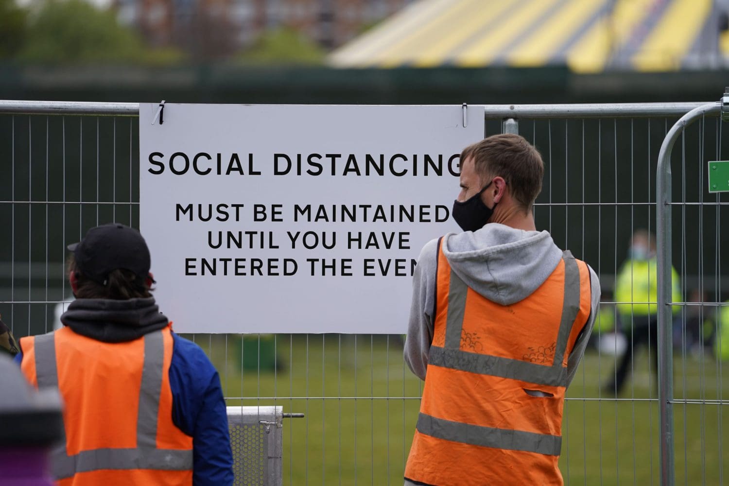 Workers besides a social distancing sign