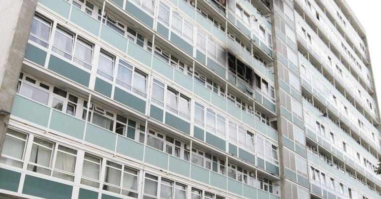 The bottom of Grenfell Tower with two police officers standing beside it
