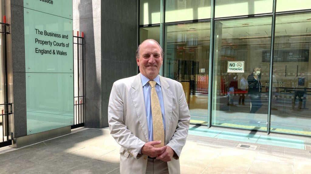 Victor over The Sun Simon Hughes smiling in front of a court room