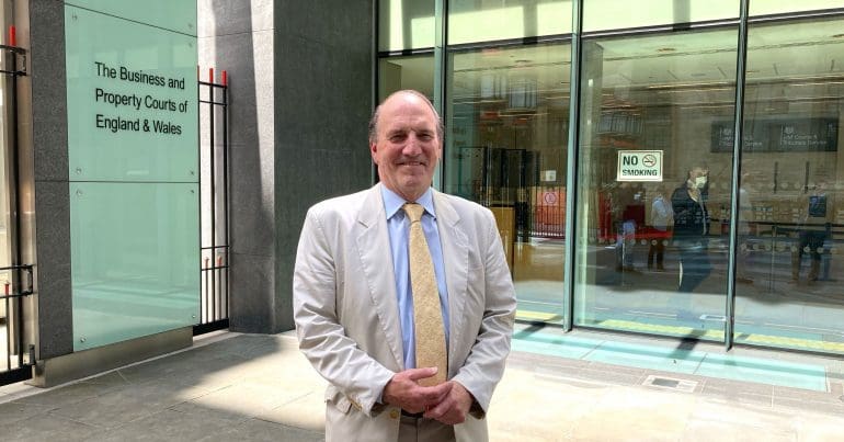 Victor over The Sun Simon Hughes smiling in front of a court room