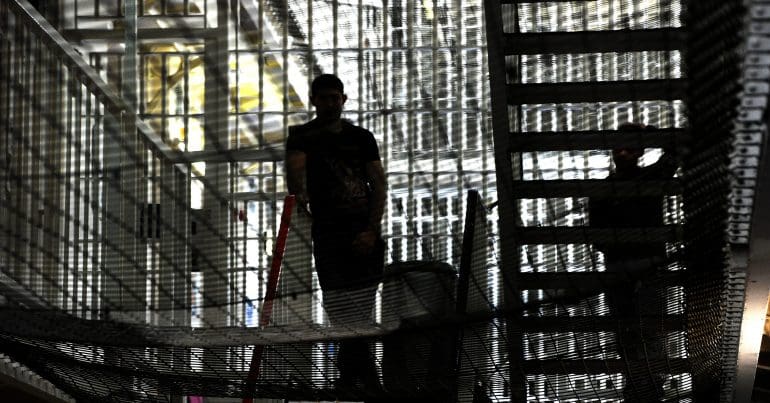 A prisoner standing in the shadows in a cell block