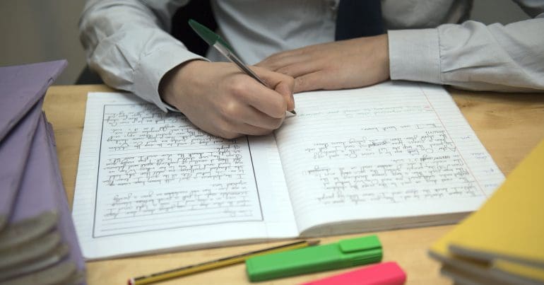 A school pupil writing in a note book