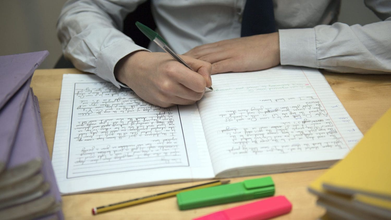 A school pupil writing in a note book