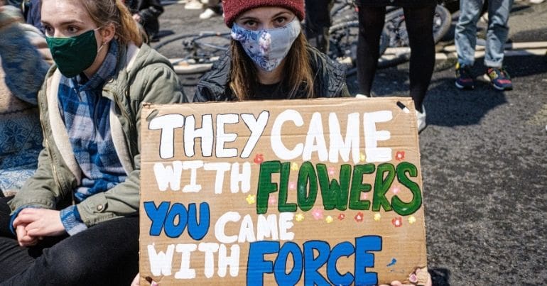 Kill the Bill protester holds sign reading: 'they came with flowers, you came with force'