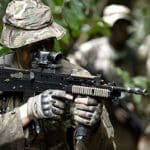 A soldier in camouflage holding a rifle