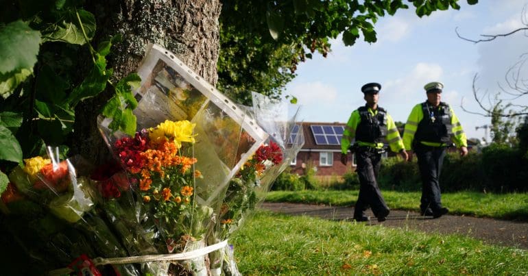 Police officers and flowers left in memory of the victims of the shooting