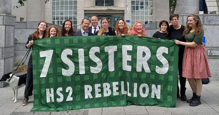 Campaigners gather outside court behind a HS2 rebellion banner
