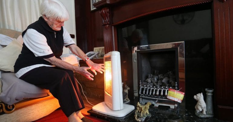 An old woman with an electric heater