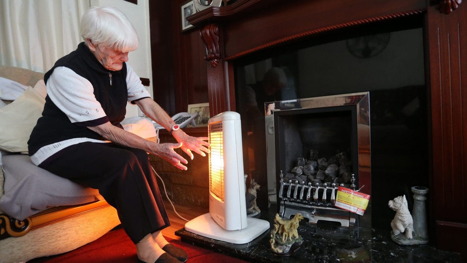 An old woman with an electric heater