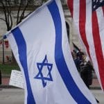 Man holding an Israeli flag and a US flag