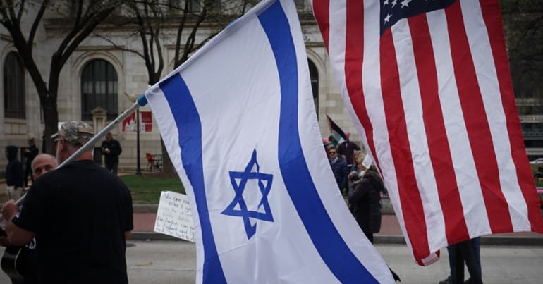 Man holding an Israeli flag and a US flag