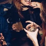 Two women talking while holding drinking glasses