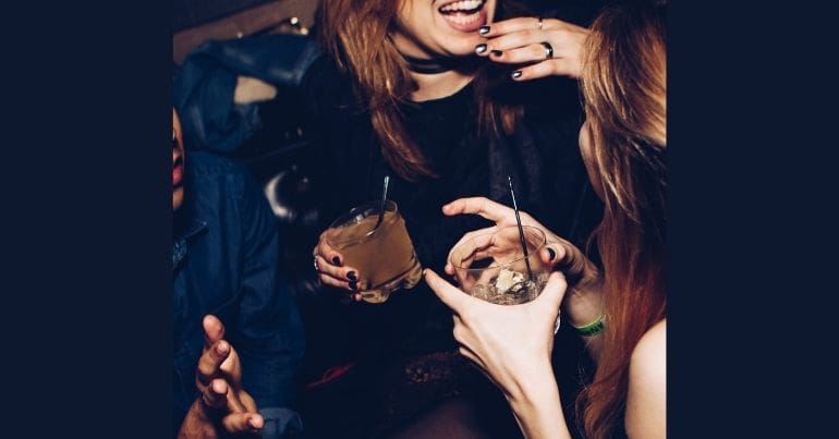 Two women talking while holding drinking glasses