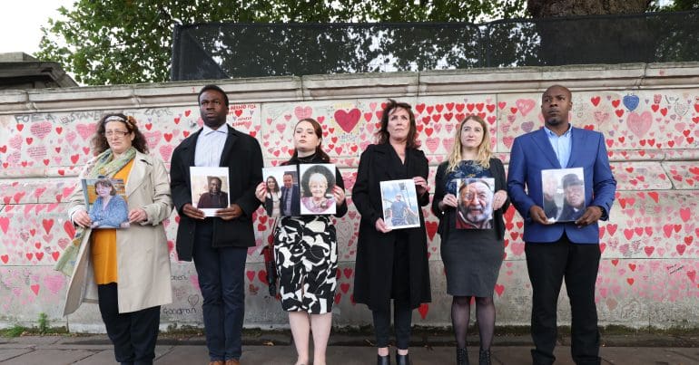 Members of The Covid-19 Bereaved Families for Justice group holding up pictures of family members
